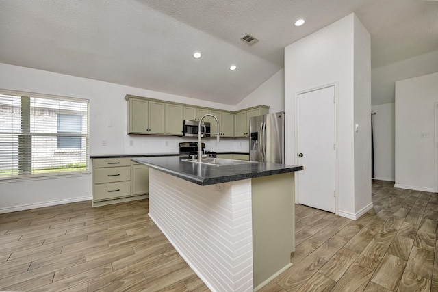 6717 Red Rock Trl, Watauga, TX 76137 - kitchen with appliances with stainless steel finishes, light wood-type flooring, dark countertops, a center island with sink, and lofted ceiling