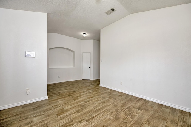 6717 Red Rock Trl, Watauga, TX 76137 - spare room featuring lofted ceiling, wood finished floors, baseboards, and a textured ceiling