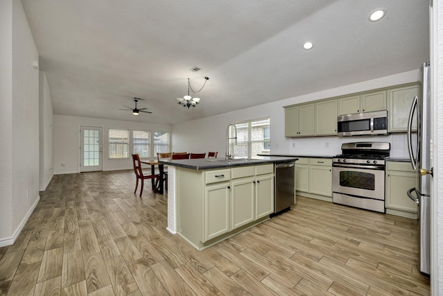 6717 Red Rock Trl, Watauga, TX 76137 - kitchen featuring stainless steel appliances, a sink, dark countertops, a chandelier, and light wood-type flooring