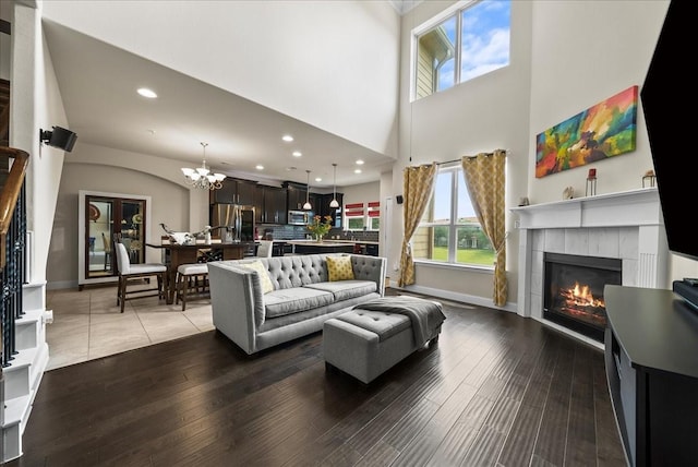 living room with a tiled fireplace, a chandelier, wood finished floors, recessed lighting, and baseboards