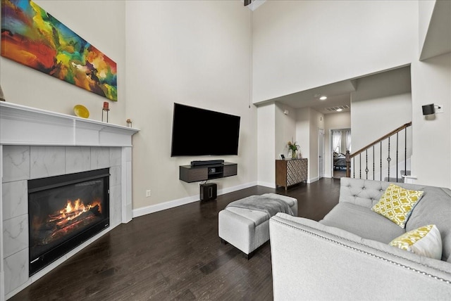 living room with wood finished floors, a towering ceiling, a fireplace, baseboards, and stairway