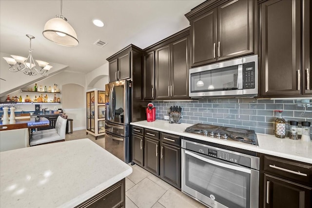 kitchen with appliances with stainless steel finishes, backsplash, arched walkways, and a chandelier