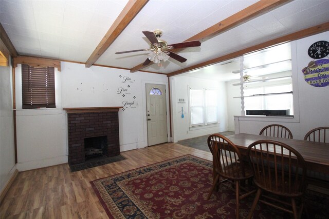 260 S Munday Ave, Munday, TX 76371 - dining room with beam ceiling, wood finished floors, a ceiling fan, a fireplace, and baseboards