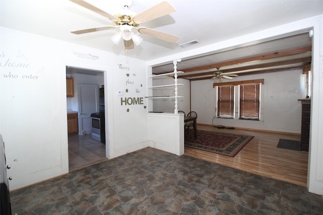 260 S Munday Ave, Munday, TX 76371 - unfurnished living room with ceiling fan, stone finish flooring, beamed ceiling, and baseboards