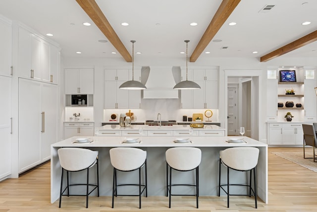 1405 Ridge Cir, Westlake, TX 76262 - kitchen featuring custom exhaust hood, beamed ceiling, white cabinets, a large island, and a sink