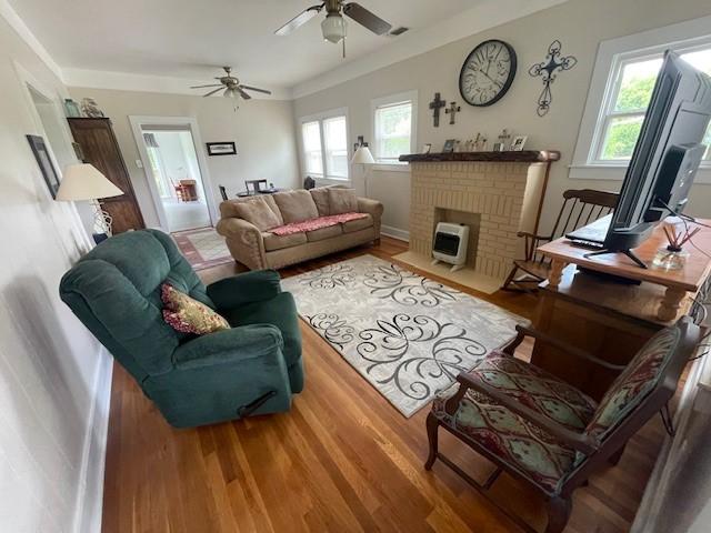 living area with a ceiling fan, wood finished floors, and a fireplace