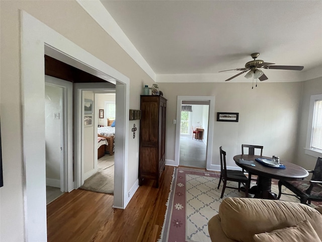 dining room with dark wood-style floors, a ceiling fan, and baseboards
