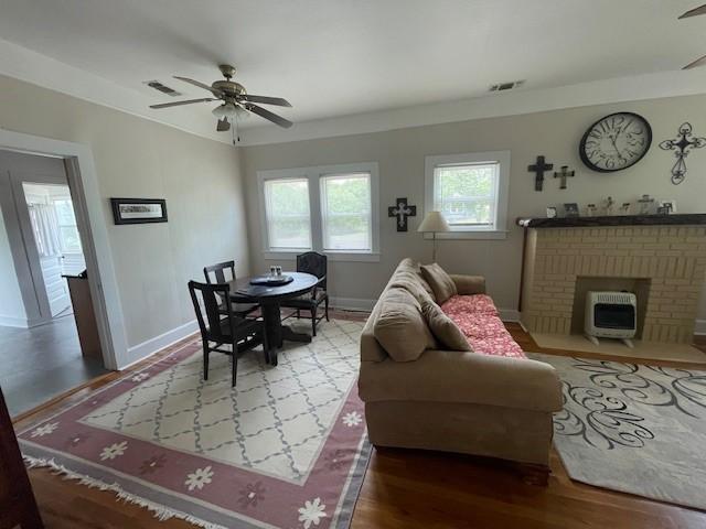 living room with a ceiling fan, heating unit, wood finished floors, and baseboards
