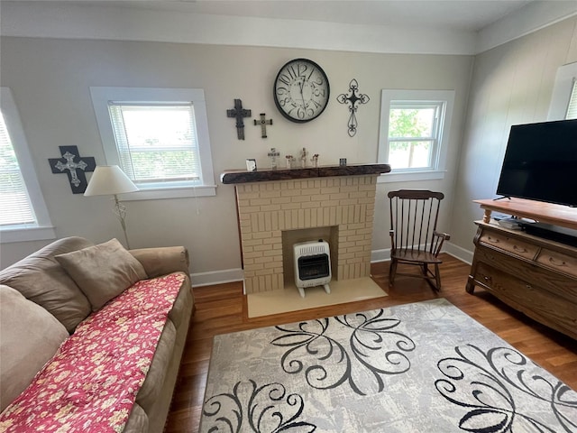 living room featuring heating unit, wood finished floors, a brick fireplace, and baseboards