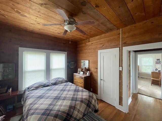 bedroom with wood ceiling, wooden walls, wood finished floors, and ceiling fan