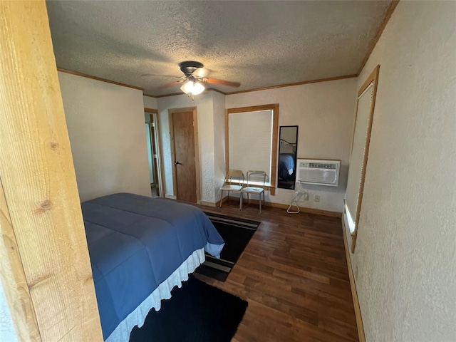 bedroom with wood finished floors, a wall unit AC, a textured ceiling, ornamental molding, and a textured wall