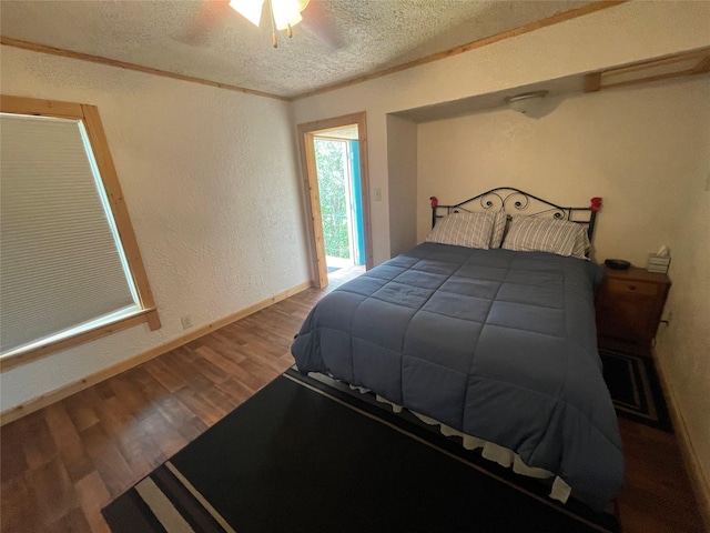 bedroom featuring a textured wall, a textured ceiling, wood finished floors, baseboards, and a ceiling fan
