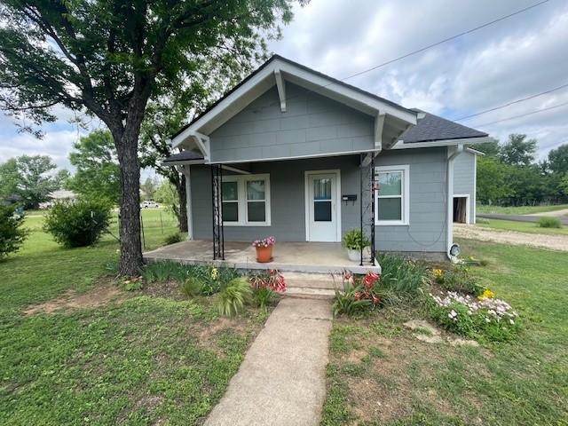 bungalow-style home featuring covered porch and a front lawn