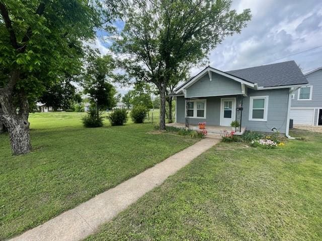 view of front of house with a porch, a front yard, and a garage