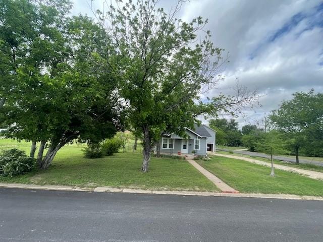 view of property hidden behind natural elements featuring a front lawn