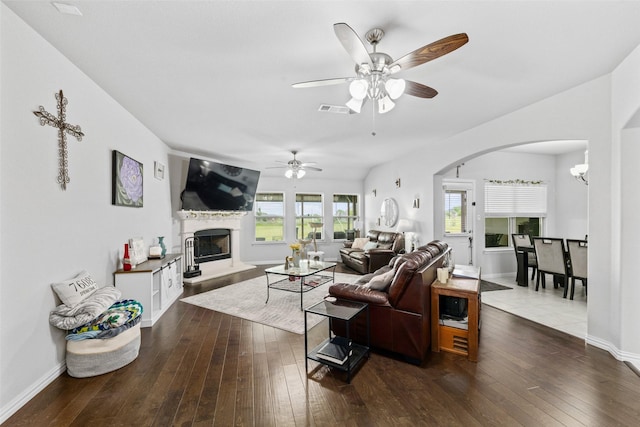 239 Springwood Ranch Loop, Springtown, TX 76082 - living area with arched walkways, a fireplace with raised hearth, dark wood-style flooring, ceiling fan, and baseboards