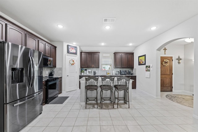 239 Springwood Ranch Loop, Springtown, TX 76082 - kitchen with appliances with stainless steel finishes, arched walkways, a kitchen bar, tasteful backsplash, and dark brown cabinets