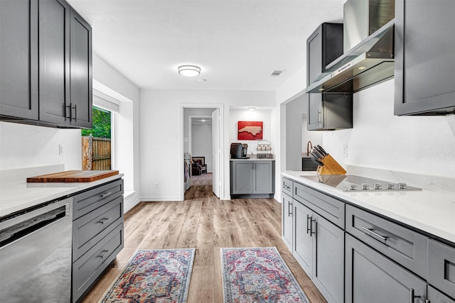 kitchen featuring dishwasher, wall chimney exhaust hood, black electric stovetop, light wood-type flooring, and light countertops