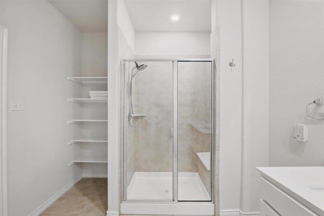 bathroom with a shower stall, vanity, tile patterned flooring, and baseboards