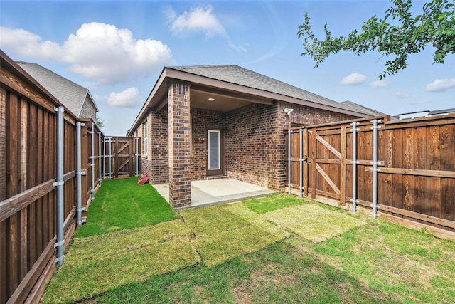 back of house featuring a gate, brick siding, a patio, and roof with shingles