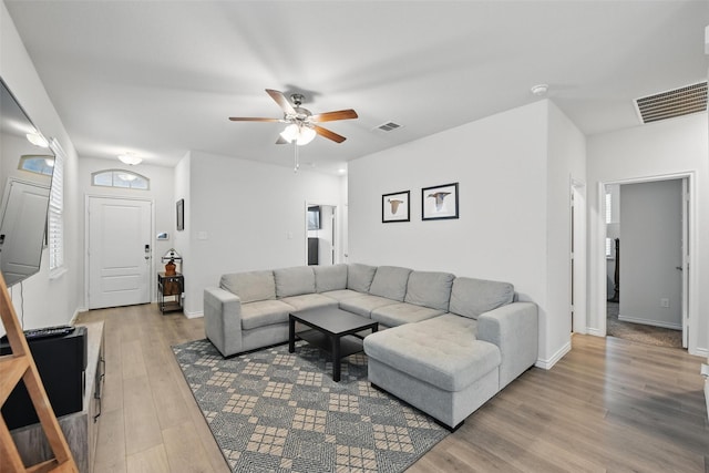 living room featuring light wood-style flooring, a ceiling fan, and baseboards