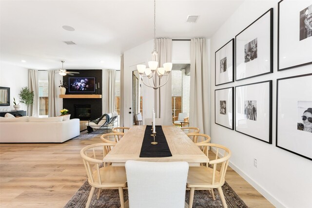 3545 W Cheney Ave, Celina, TX 75009 - dining area featuring light wood-style floors, a chandelier, a large fireplace, baseboards, and a ceiling fan