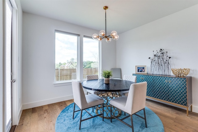 dining space featuring a chandelier, baseboards, and wood finished floors