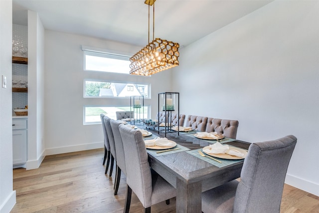 dining room featuring light wood-type flooring, baseboards, and a chandelier