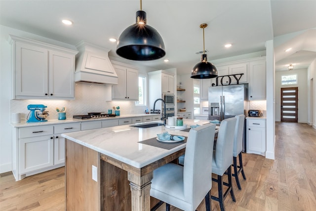 kitchen with custom range hood, appliances with stainless steel finishes, a sink, tasteful backsplash, and light countertops