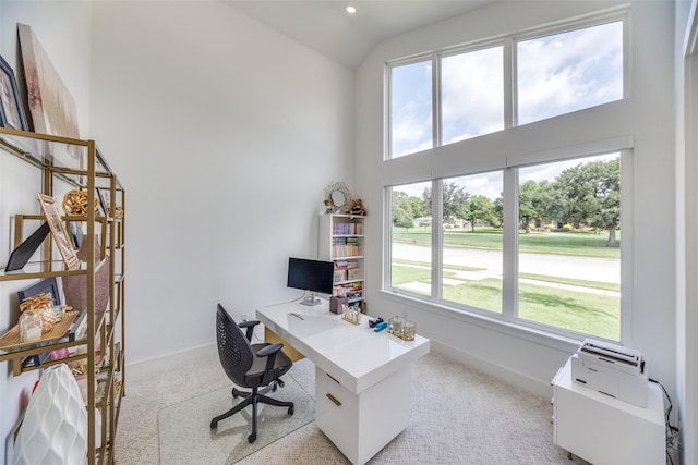 office space featuring light colored carpet, baseboards, and high vaulted ceiling