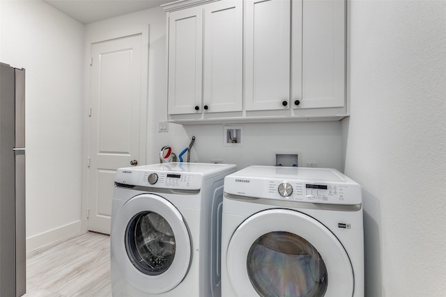 washroom featuring cabinet space, baseboards, washer and clothes dryer, and light wood-type flooring
