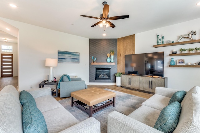 living room featuring ceiling fan, wood finished floors, a large fireplace, and recessed lighting