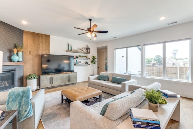 living room featuring ceiling fan, wood finished floors, a fireplace, recessed lighting, and baseboards