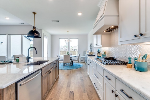 kitchen featuring a sink, stainless steel appliances, custom exhaust hood, light wood-style flooring, and white cabinets