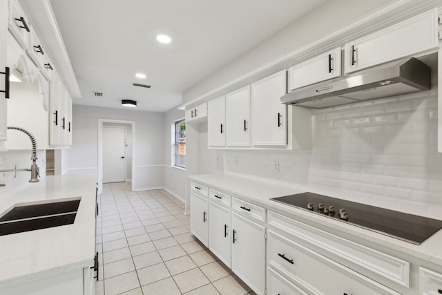 kitchen with under cabinet range hood, a sink, decorative backsplash, light tile patterned floors, and black electric stovetop