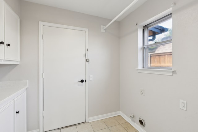 washroom featuring hookup for an electric dryer, cabinet space, plenty of natural light, and light tile patterned floors