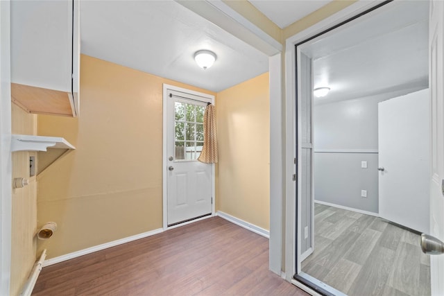 doorway featuring wood finished floors and baseboards
