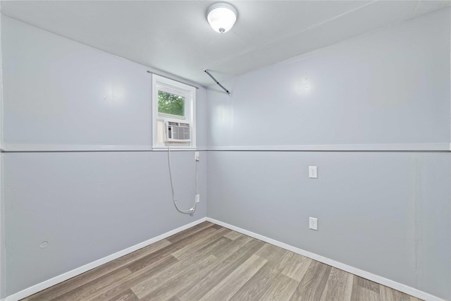 basement with wood finished floors, baseboards, and cooling unit
