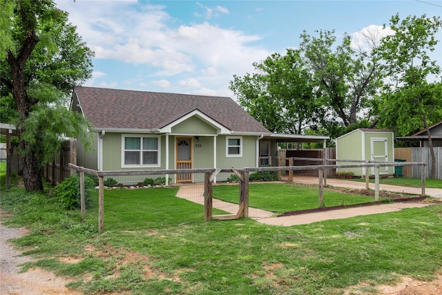 view of front of home with covered porch, roof with shingles, a storage unit, and an outbuilding