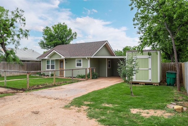 view of front of home with driveway, a storage unit, an attached carport, an outdoor structure, and a shingled roof