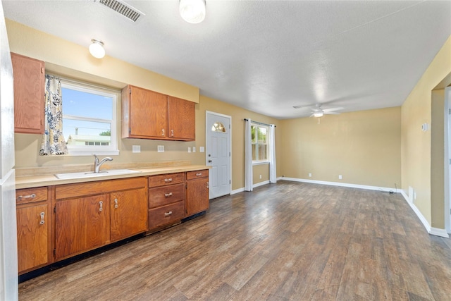 kitchen featuring a sink, brown cabinetry, dark wood finished floors, and light countertops