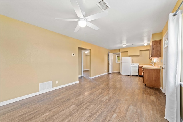 unfurnished living room with wood finished floors, a ceiling fan, and baseboards