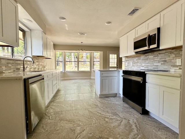5711 Trail Lake Dr, Arlington, TX 76016 - kitchen with appliances with stainless steel finishes, a sink, light countertops, white cabinets, and tasteful backsplash