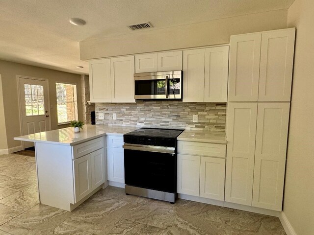 5711 Trail Lake Dr, Arlington, TX 76016 - kitchen with range with electric stovetop, stainless steel microwave, a peninsula, decorative backsplash, and light countertops