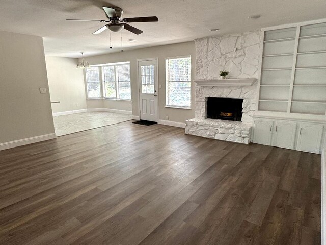 5711 Trail Lake Dr, Arlington, TX 76016 - unfurnished living room featuring a ceiling fan, a stone fireplace, baseboards, dark wood-type flooring, and a textured ceiling