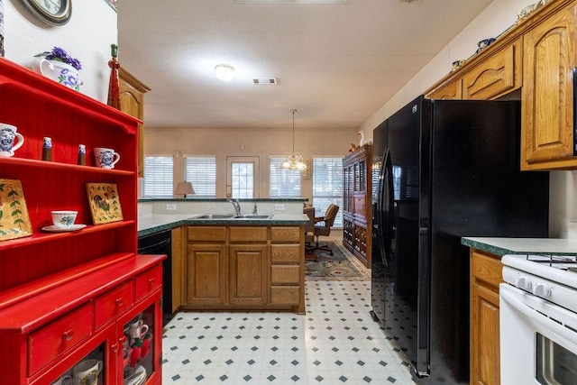 600 Hanover Dr, Waxahachie, TX 75165 - kitchen with black appliances, brown cabinets, light flooring, a peninsula, and hanging light fixtures