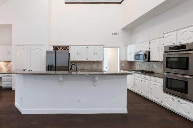 7100 Oakbrook Dr, Plano, TX 75025 - kitchen with appliances with stainless steel finishes, tasteful backsplash, dark stone counters, white cabinets, and a towering ceiling