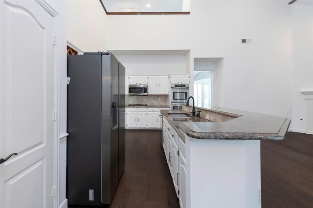 7100 Oakbrook Dr, Plano, TX 75025 - kitchen with stainless steel appliances, white cabinets, a sink, dark wood-style floors, and tasteful backsplash