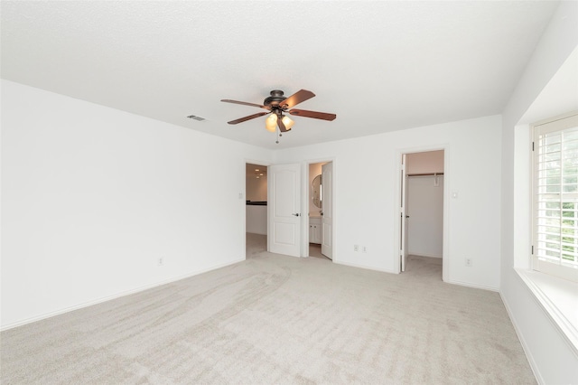 7100 Oakbrook Dr, Plano, TX 75025 - unfurnished bedroom with a walk in closet, light carpet, a closet, and a ceiling fan