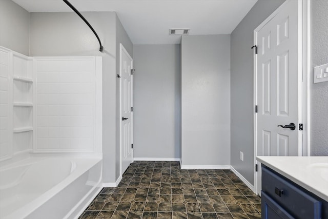 bathroom with bathtub / shower combination, vanity, baseboards, and stone finish flooring